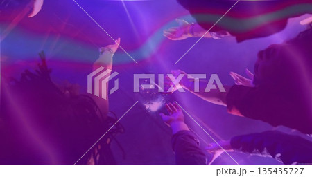 Dancing partygoers raising arms toward mirrored disco ball at club floor, with bracelets and fog 135435727