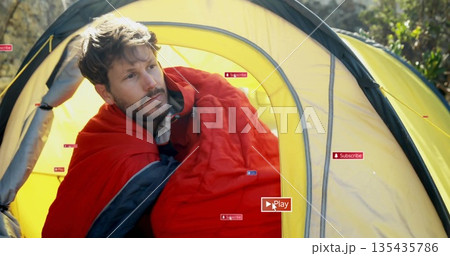 Sitting middle-aged man adjusting red sleeping bag at forest campsite with yellow dome tent Sitting middle-aged man adjusting red sleeping bag at forest campsite with yellow dome tent 135435786