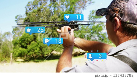 Adjusting man in baseball cap tuning black drone amid trees with social media icons, copy space 135435798