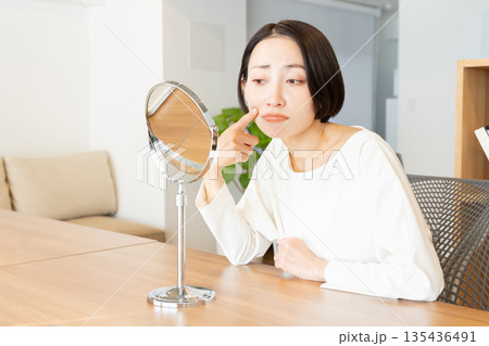 鏡を見て肌の調子を悩む気にする女性 135436491
