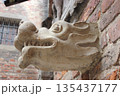 Stone gargoyle head carved into historic brick wall 135437177