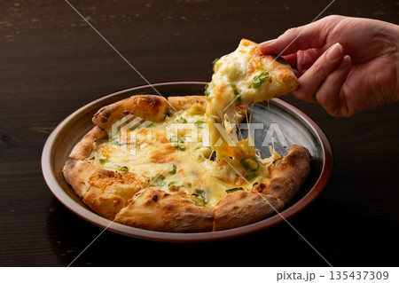《とろけるチーズを引き上げるピザの一切れ》 135437309
