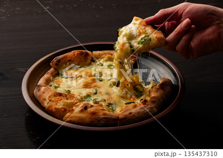 《伸びるチーズを持ち上げる焼きたてピザ》 135437310