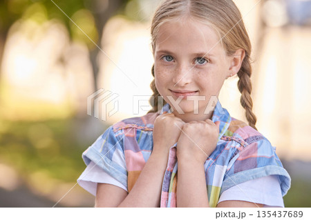 Cute caucasian young girl with braids smiling outdoors in colorful shirt 135437689