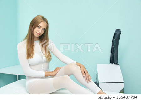 Young caucasian female in white outfit relaxing on spa bed in modern wellness 135437704