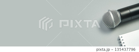 Microphone and open notebook on gray background for music, speech, or podcast 135437796