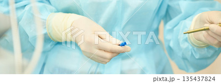 Close-up of medical professionals gloved hands preparing blue connector Close-up of medical professionals gloved hands preparing blue connector 135437824