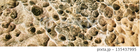 Natural eroded rock surface with unique patterns and textures in earthy tones 135437995