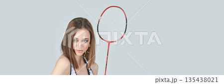 Caucasian female young adult holding badminton racket against gray background 135438021