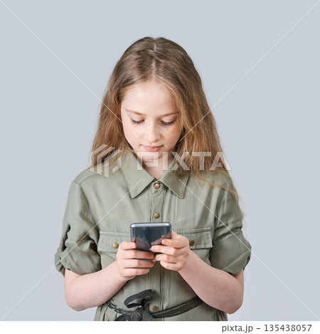 Caucasian young girl using smartphone in gray outfit on light background 135438057