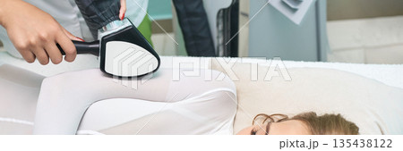 Female undergoing laser hair removal treatment on legs in medical clinic 135438122