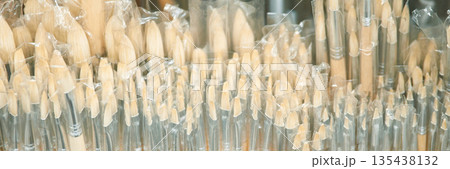 Close-up of multiple wooden art brushes with transparent plastic covers 135438132