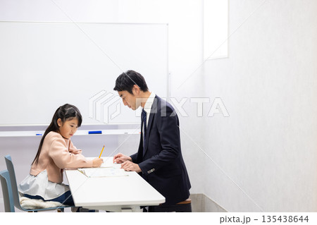 塾の先生に勉強を教わる小学生の女の子 135438644