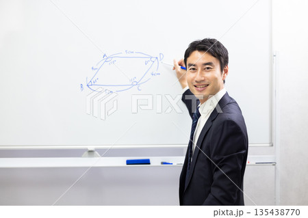 ホワイトボードを使って算数を教える笑顔の塾講師 135438770