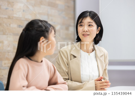 小学生の女の子と話すスーツ姿の母親 小学生の女の子と話すスーツ姿の母親 135439044