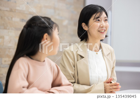 小学生の女の子と話すスーツ姿の母親 小学生の女の子と話すスーツ姿の母親 135439045