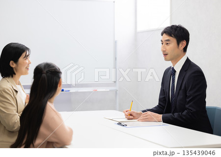 女子児童と母親と三者面談をする男性塾講師 135439046