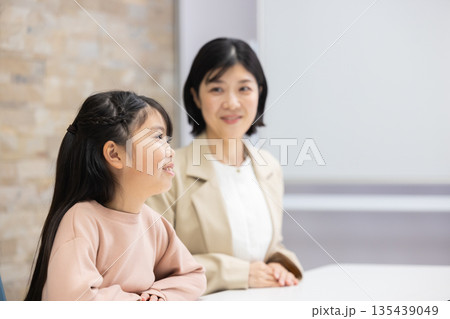 小学生の女の子と話すスーツ姿の母親 135439049