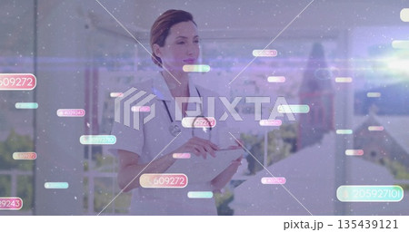 Examining data on tablet nurse in scrubs with stethoscope on balcony with data overlays, copy space Examining data on tablet nurse in scrubs with stethoscope on balcony with data overlays, copy space 135439121