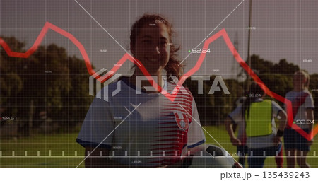 Smiling teenage soccer player in striped jersey holding ball on grass field, with AR graph overlay 135439243