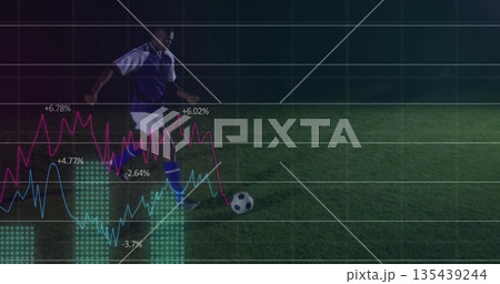 Striking soccer player in blue kit kicking ball on grass pitch, with digital chart overlays 135439244