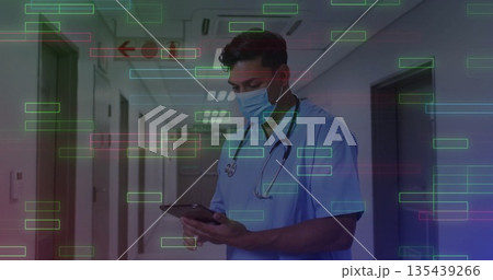 Doctor wearing scrubs and mask reviewing records in hospital corridor, with tablet and stethoscope 135439266
