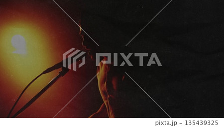 Performing shirtless male vocalist singing on club stage, with microphone and glowing stage light 135439325