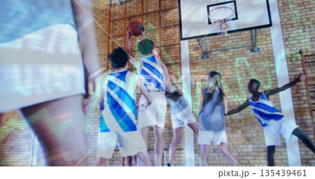 Jumping teenage boy in blue-and-white jersey grabbing basketball in gym, with hoop and backboard 135439461