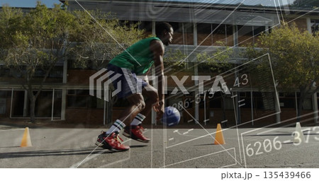Dribbling player in green jersey maneuvering cones on schoolyard court with basketball and overlay 135439466