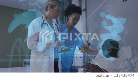 Examining medical team reviewing patient data on tablet in hospital room, with holographic graphics Examining medical team reviewing patient data on tablet in hospital room, with holographic graphics 135439474