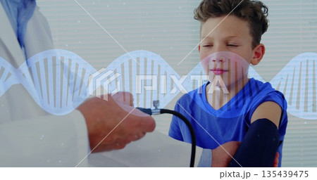 Measuring boy's blood pressure while doctor inflating cuff in exam room with DNA helix, copy space Measuring boy's blood pressure while doctor inflating cuff in exam room with DNA helix, copy space 135439475