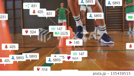 Navigating athlete in green uniform performing agility drill in gym, with orange cones, media icons 135439515