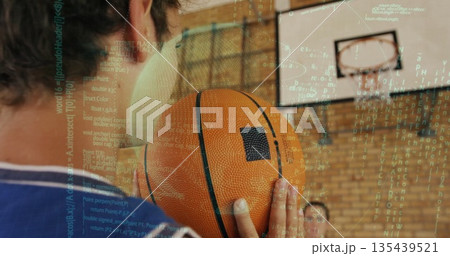 Holding basketball, boy in jersey preparing shot in gym, with hoop and code overlay, copy space Holding basketball, boy in jersey preparing shot in gym, with hoop and code overlay, copy space 135439521
