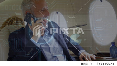 Talking traveler wearing navy blazer in jet cabin with smartphone, leather seats and oval window 135439574