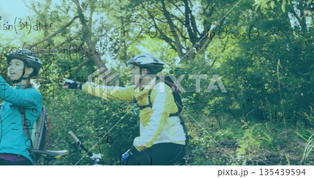 Pausing cyclists on mountain bikes wearing jackets and helmets on forest trail, with math equations 135439594