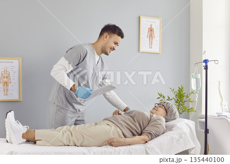 Sick senior patient lying on the couch in hospital receiving IV drip infusion. 135440100