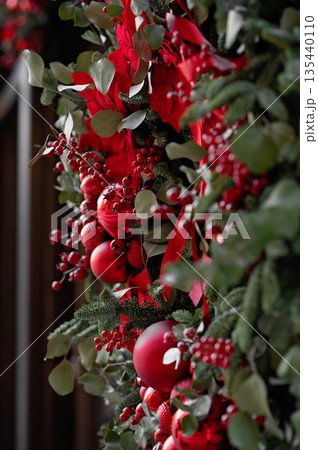 Festive red and green holiday wreath with ornaments and ribbons, close-up view with copy space Festive red and green holiday wreath with ornaments and ribbons, close-up view with copy space 135440110