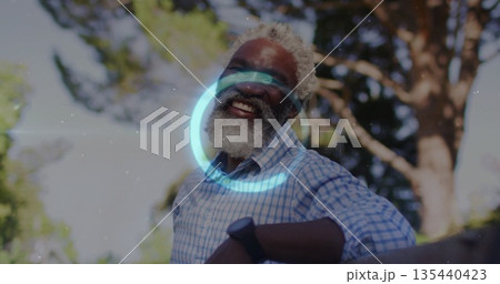 Smiling senior man leaning against wooden railing in garden, with checkered shirt and wristwatch Smiling senior man leaning against wooden railing in garden, with checkered shirt and wristwatch 135440423
