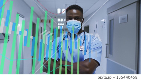 Standing doctor wearing scrubs and mask in hospital corridor with stethoscope and overlays 135440459