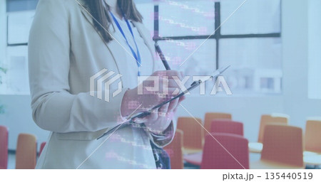 Standing businesswoman holding clipboard and pen in training room with chairs, badge, code overlay Standing businesswoman holding clipboard and pen in training room with chairs, badge, code overlay 135440519