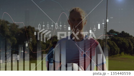 Showing soccer player wearing jersey holding ball on sports field, with financial charts overlaying 135440559
