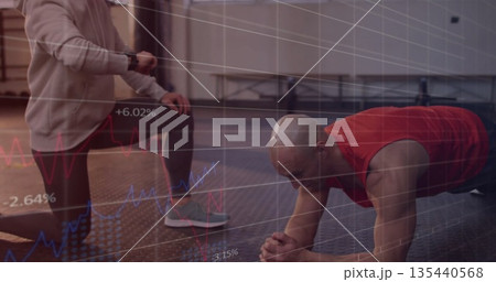 Performing plank exercise man on rubber mat at gym with kneeling trainer, showing financial charts Performing plank exercise man on rubber mat at gym with kneeling trainer, showing financial charts 135440568