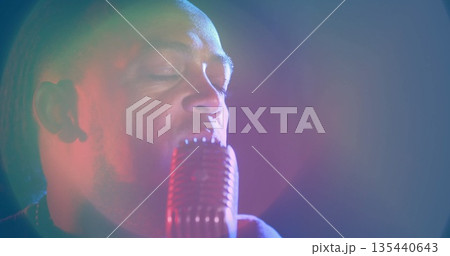 Singing male singer wearing dark shirt, holding retro microphone on stage with colored spotlights Singing male singer wearing dark shirt, holding retro microphone on stage with colored spotlights 135440643
