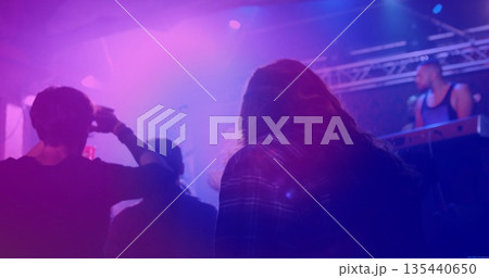 Watching long-haired man wearing plaid shirt shading eyes at music venue, with keyboard rig haze Watching long-haired man wearing plaid shirt shading eyes at music venue, with keyboard rig haze 135440650