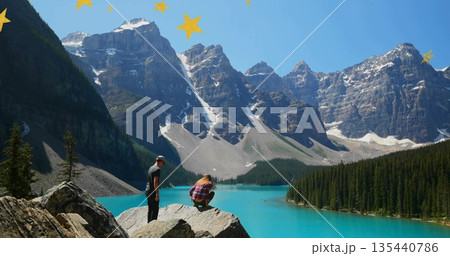 Watching couple on boulder overlooking turquoise lake, snow-capped peaks, star overlays, copy space Watching couple on boulder overlooking turquoise lake, snow-capped peaks, star overlays, copy space 135440786