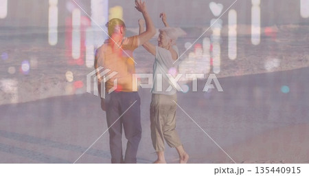 Dancing barefoot couple raising arms on wet beach sand, with sea waves reflections Dancing barefoot couple raising arms on wet beach sand, with sea waves reflections 135440915