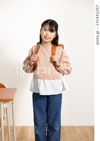 学校の教室でランドセルを背負って微笑む小学生の女の子 135442267
