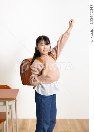 学校の教室でガッツポーズをするランドセルを背負った笑顔の小学生の女の子 学校の教室でガッツポーズをするランドセルを背負った笑顔の小学生の女の子 135442347