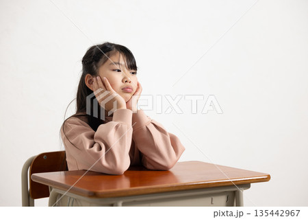 退屈そうな顔で頬杖をつく小学生の女の子 退屈そうな顔で頬杖をつく小学生の女の子 135442967