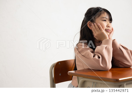 退屈そうな顔で頬杖をつく小学生の女の子 退屈そうな顔で頬杖をつく小学生の女の子 135442971